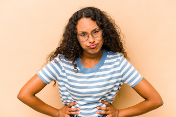 Wall Mural - Young hispanic woman isolated on beige background sad, serious face, feeling miserable and displeased.