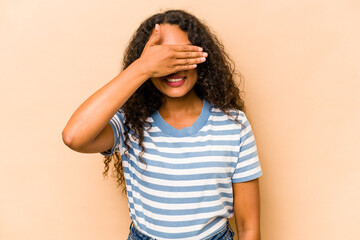 Wall Mural - Young hispanic woman isolated on beige background covers eyes with hands, smiles broadly waiting for a surprise.