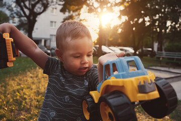 Wall Mural - Kid playing with toys outside. Child having fun on playground in sunset. Outdoor creative activities for kids. Summer and childhood concept