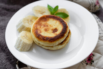 two curd fritters with sliced banana in a white plate