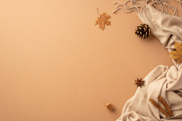 Autumn aesthetic concept. Top view photo of yellow maple leaves cinnamon sticks anise pine cones and scarf on isolated beige background with empty space