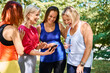 Diverse group of women looking at mobile phone during outdoor workout in park