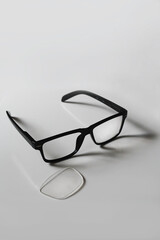 Broken pair of black reading glasses set against a white background with copy space available