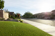 © StudioWout - Suburban front yard with artificial grass lawn next to sidewalk and street