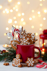 Christmas composition with gingerbread cookies, candy cane and marshmallow in a red mug. Cozy home atmosphere, delicious sweet holiday dessert. Traditional spices: cinnamon, anise, cardamom