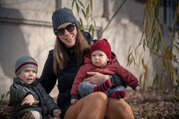 Wall Mural - Mamá con sus hijos bebé y niño disfrutando del otoño invierno entre los árboles