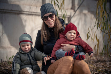 Wall Mural - Mamá con sus hijos bebé y niño disfrutando del otoño invierno entre los árboles