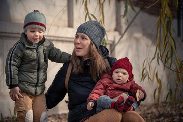 Wall Mural - Mamá con sus hijos bebé y niño disfrutando del otoño invierno entre los árboles