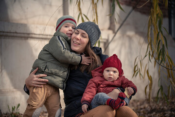 Wall Mural - Mamá con sus hijos bebé y niño disfrutando del otoño invierno entre los árboles