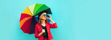 Portrait Of Happy Smiling Young Woman Photographer With Film Camera And Colorful Umbrella On Blue Background, Blank Copy Space For Advertising Text