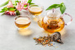 Hot lemongrass tea in a glass teapot on a light background decorated with flowers