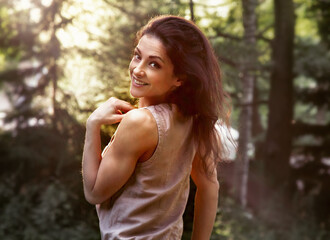 Wall Mural - Beautiful enjoying young woman relaxing with long healthy bright hair on nature bright sunny summer sunset yellow orange rays in the park trees background. Happy