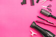 Scissors, combs, brushes, hair dryer, hair straightener and hairpin on a pink background.