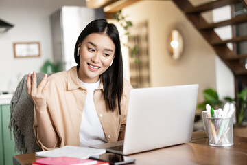 Smiling asian woman talks on video conference, working from home remotely with laptop, studying at online course or attending lecture