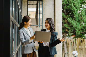 Two young friends of business woman standing and talking during lunch break front office.