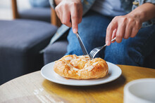 Closeup Image Of A Woman Holding And Eating A Fresh Almond Croissant With Knife And Fork