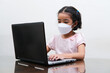 © KrishnaTedjo - Asian little girl wearing medical mask joining online school from home