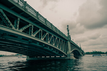 Bridge. A low metal bridge across the river in cloudy weather in gloomy dark colors. St. Petersburg