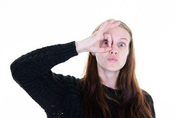 cheerful cute young woman making binocular sign with fingers on face