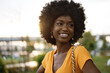 © fotofabrika - Portrait of a young african american woman smiling standing at the city.