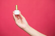 © Yuliia Sukharieva - Female's hand holding bottle nail polish on pink background.