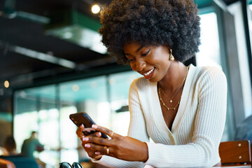 Young afro woman using mobile phone at coffee shop