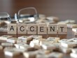 accent word or concept represented by wooden letter tiles on a wooden table with glasses and a book