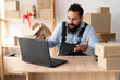© Andrii Lysenko - Evil bearded male business owner sitting at table and calling while browsing on laptop. sme business freelance working in home office using computer, online marketing packaging box delivery,