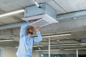 Caucasian bearded man repairing the air conditioner in the office. 