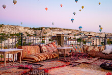 Terrace Of Hotel In Goreme Cappadocia And Hot Air Balloons Rising Into Sky, Concept  Of Must See Travel Destination, Bucket List Trip