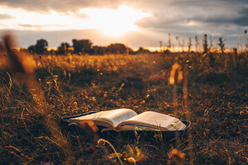 Canvas Print - Open bible on the field at sunset