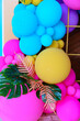© andrey - bright multi-colored photo zone with balloons and tropical leaves.
