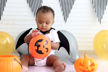 Adorable African baby kid dressing up in vampire fancy Halloween costume with black bat wings, cheerful little cute child go to party, playing trick or treat, Happy Halloween celebration.