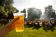 © 9parusnikov - A plastic glass of beer in hand. Outdoor summer festival.