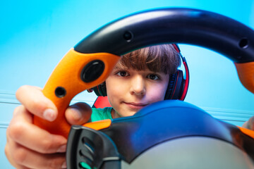 Wall Mural - Close portrait through the console steering wheel of a gamer boy