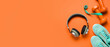 Leinwandbild Motiv Sports shoes with headphones, measuring tape and dumbbells on orange background with space for text