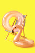 Leinwandbild Motiv Wooden deck chair with inflatable rings on yellow background