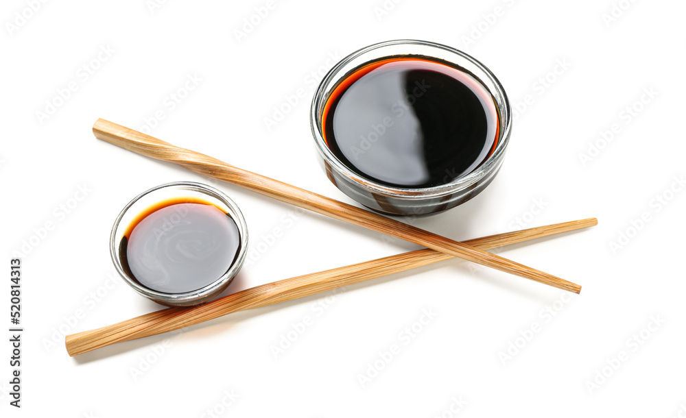 Bowls of soy sauce and chopsticks on white background