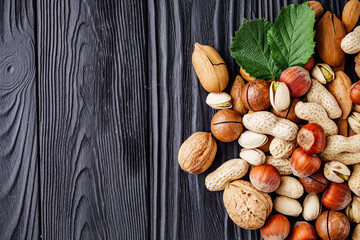 set of different nuts on a black rustic wooden background