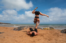 Girlfriend And Boyfriend Doing Acro Yoga Near Sea