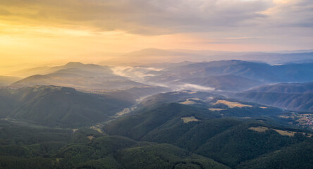 Wall Mural - Amazing view of beautiful low clouds creeping on the tree-covered mountain slopes, the Rhodopes in Bulgaria at sunrise.