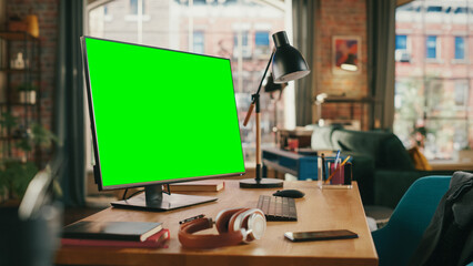 Fototapete - Desktop Computer with Mock Up Green Screen Display Standing on a Desk in Cozy Living Room. In the Background Stylish Modern Bright Home Office Studio During Day with Big Cityscape Window.