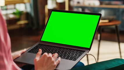 Poster - young adult woman working from home loft apartment on laptop computer with green screen mock up disp