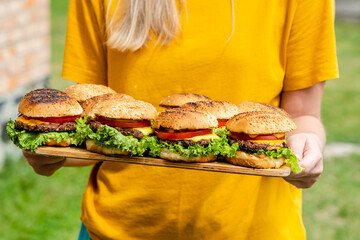 Closeup of homemade burgers made from fresh vegetables on wood plate holding women