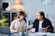 © Seventyfour - Portrait of two smiling modern women using laptops and communicating while working from home together