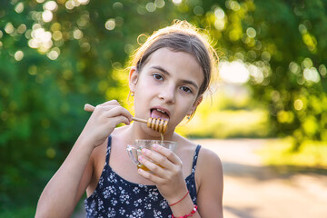 A child eats honey in the park. Selective focus.