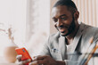 © VK Studio - Smiling african american businessman using mobile, chatting online while sitting at office desk