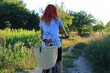 A bicycle trip of a red-haired woman with her dog in a basket.
Wycieczka rowerowa rudowłosej kobiety z psem w koszyku.