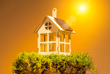 Eco housing concept,  toy house with solar panel on roof on land plot with green grass