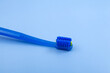 Special toothbrush for braces on blue background. Comfortable Teeth cleaning brush with bracket groove. Dental equipment. Selective focus, copy space. Design element